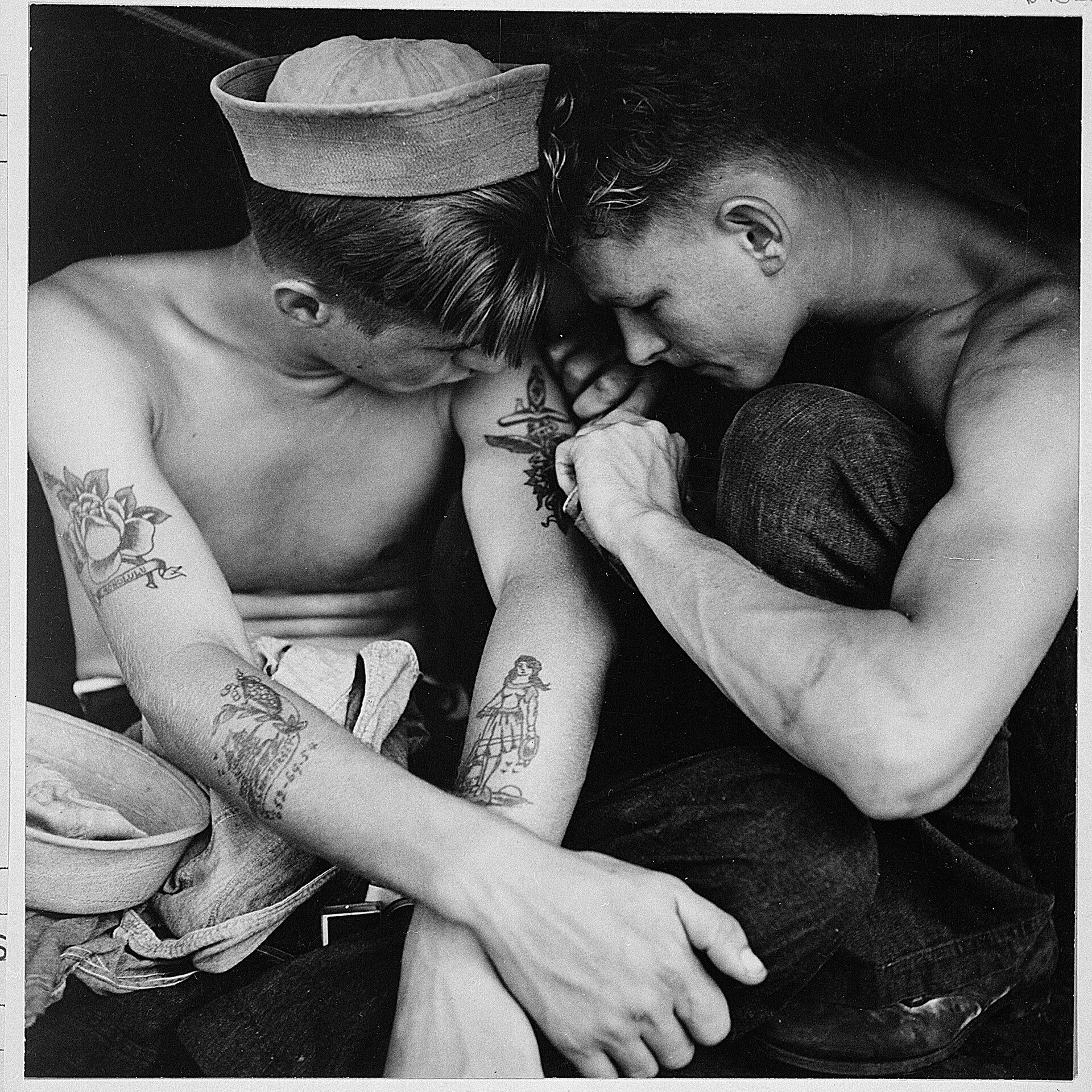 Un marinero tatúa el brazo de un compañero a bordo del USS New Jersey en 1944. Fotografía de archivo.